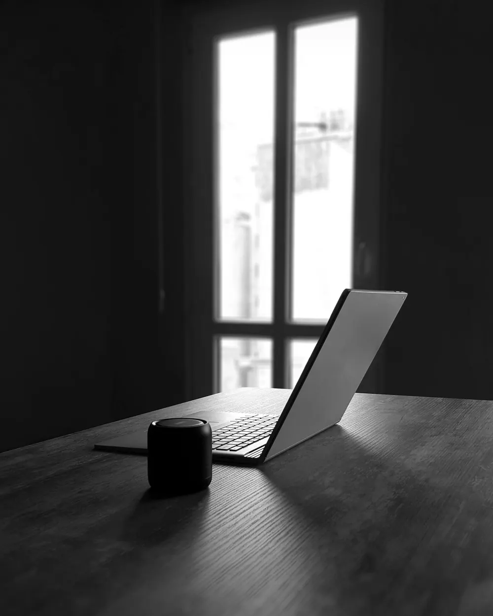 Laptop on a dark desk beside a window